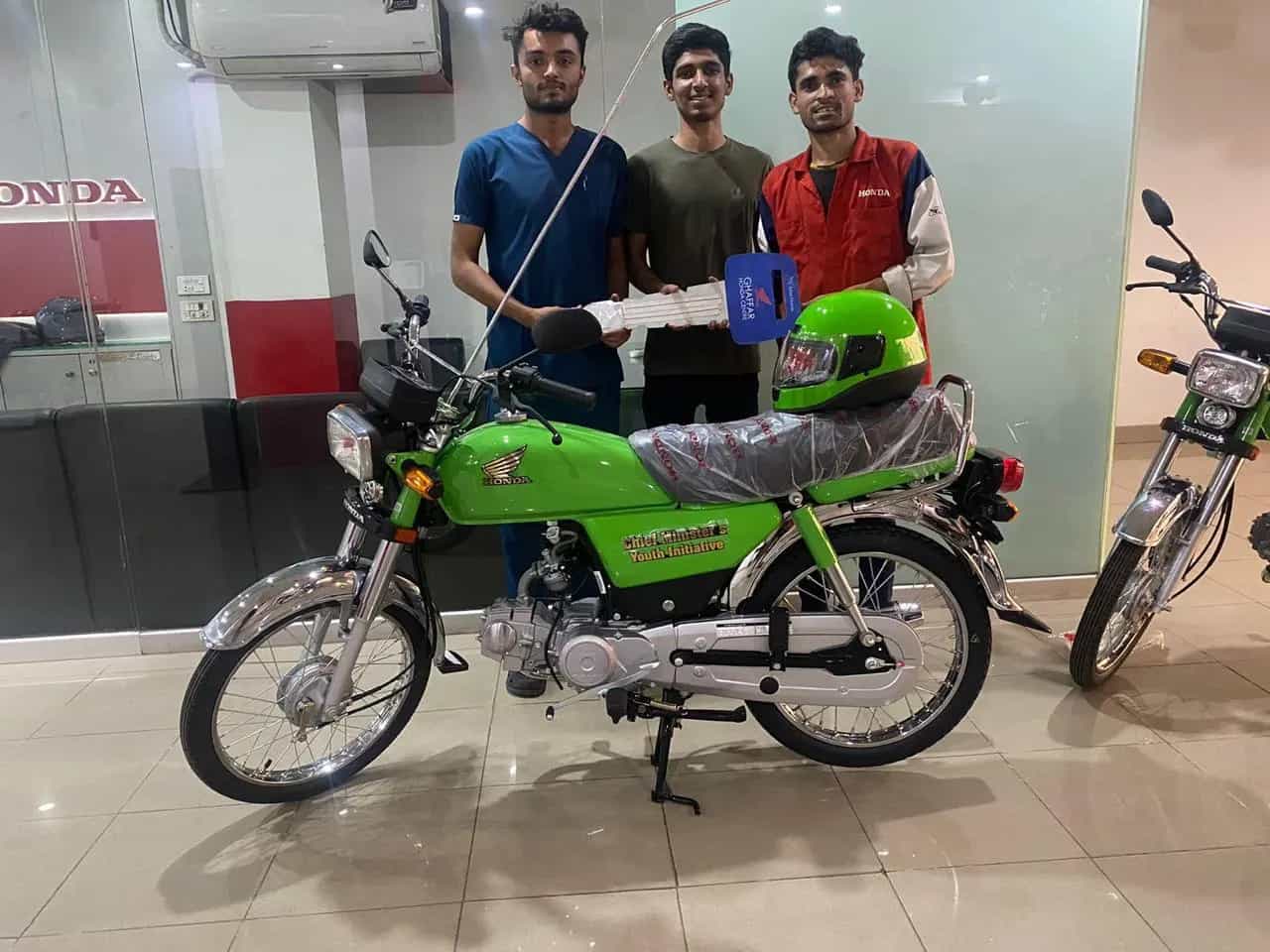 Three young students posing with a new green Chief Minister's Youth Initiative Honda bike
