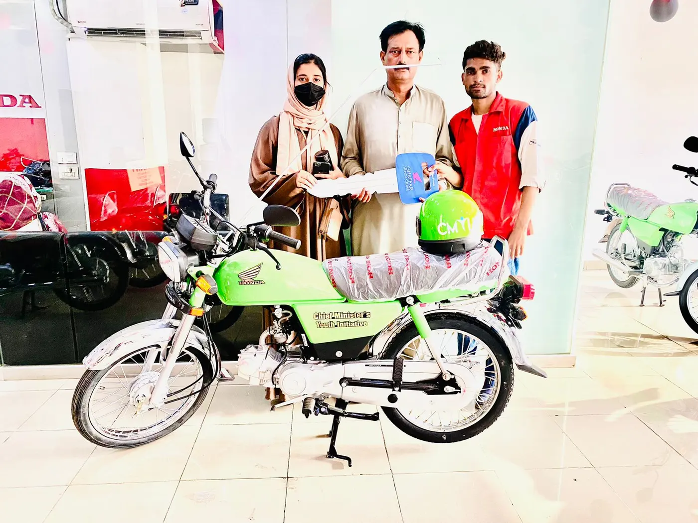 Students receiving guidance and their new bikes at an authorized scheme dealership