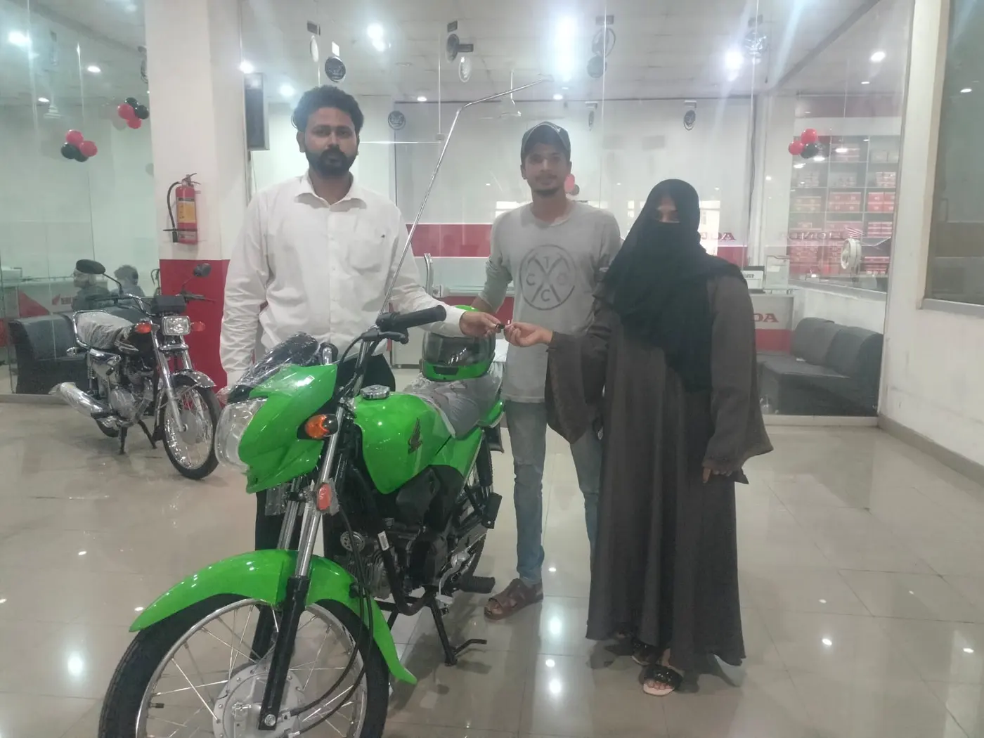 A family celebrating a green Honda scheme bike handover